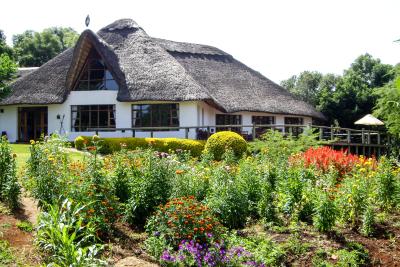 Det charmerende gamle hovedhus på Ngorongoro Farm House - med en stork på det stråtækte tag