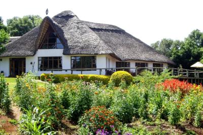 Det charmerende gamle hovedhus på Ngorongoro Farm House - med en stork på det stråtækte tag